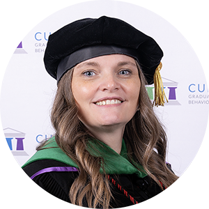 DBH graduate Dr. Holly Hanley smiling in academic regalia and doctoral tam.