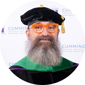 DBH graduate Dr. Jason Sargent smiling in academic regalia and doctoral tam.