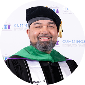 DBH graduate Dr. Jose Mathew smiling in academic regalia and doctoral tam.
