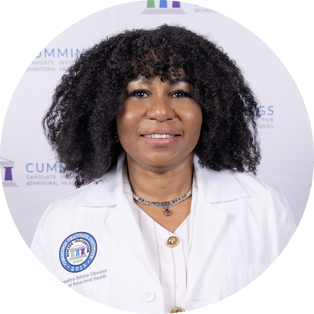 Circular headshot of Roseline smiling in a white lab coat featuring the Cummings Graduate Institute for Behavioral Health Studies emblem, with curly black hair and a CGI-branded backdrop.